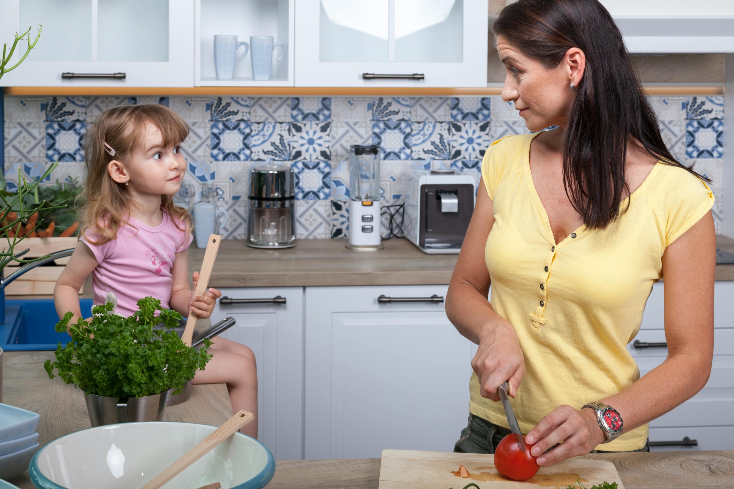 mother and daughter chatting while cooking mother and daughter chatting while cooking